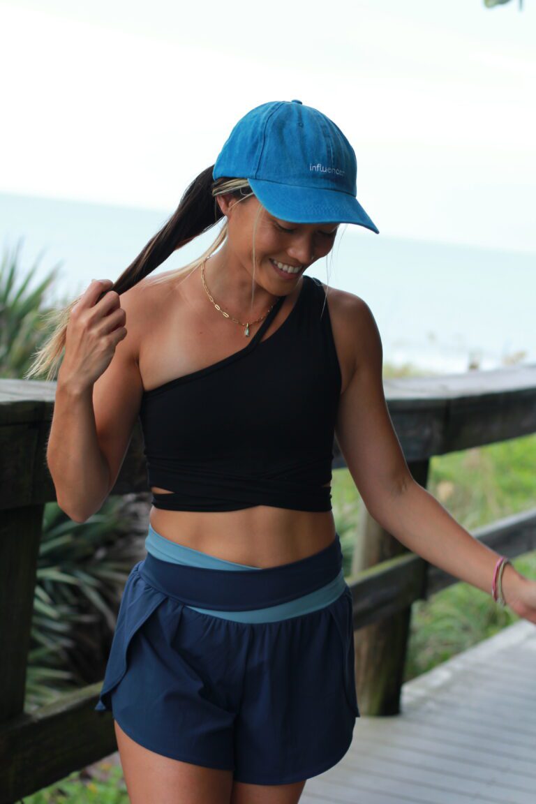 Woman in a black one-shoulder top outdoors — coastal living in your 30s