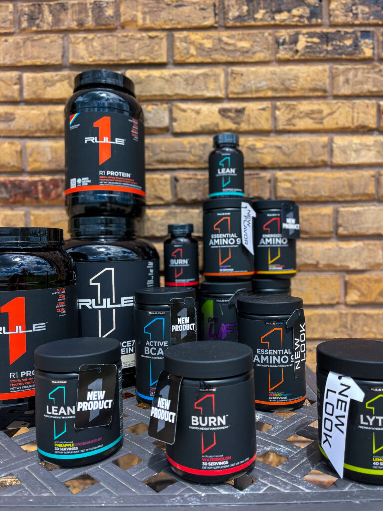 A lineup of Rule One protein and supplement tubs