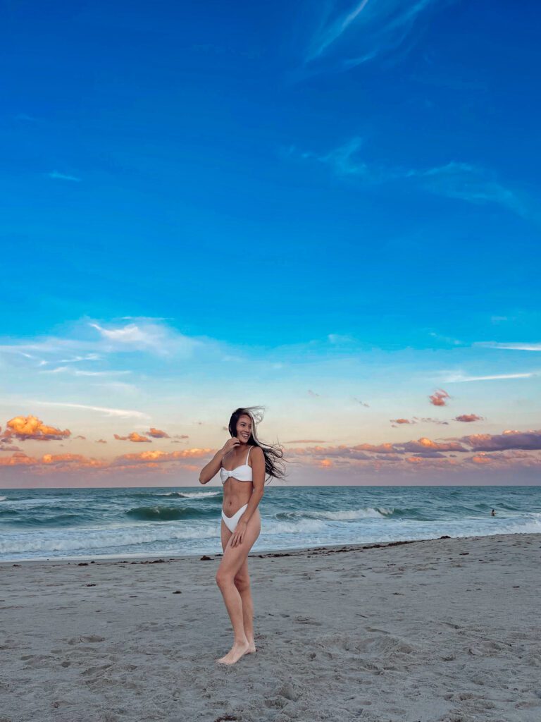 Woman in her 30s posing in white bikini on Florida beach at sunset