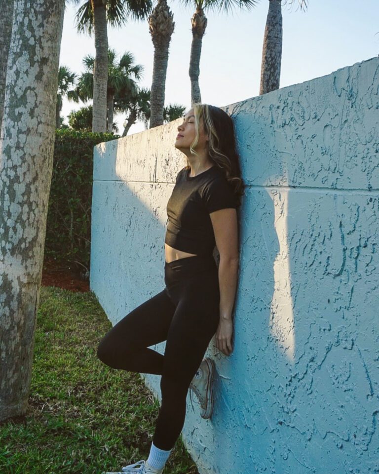 Woman in a black outfit by a blue wall