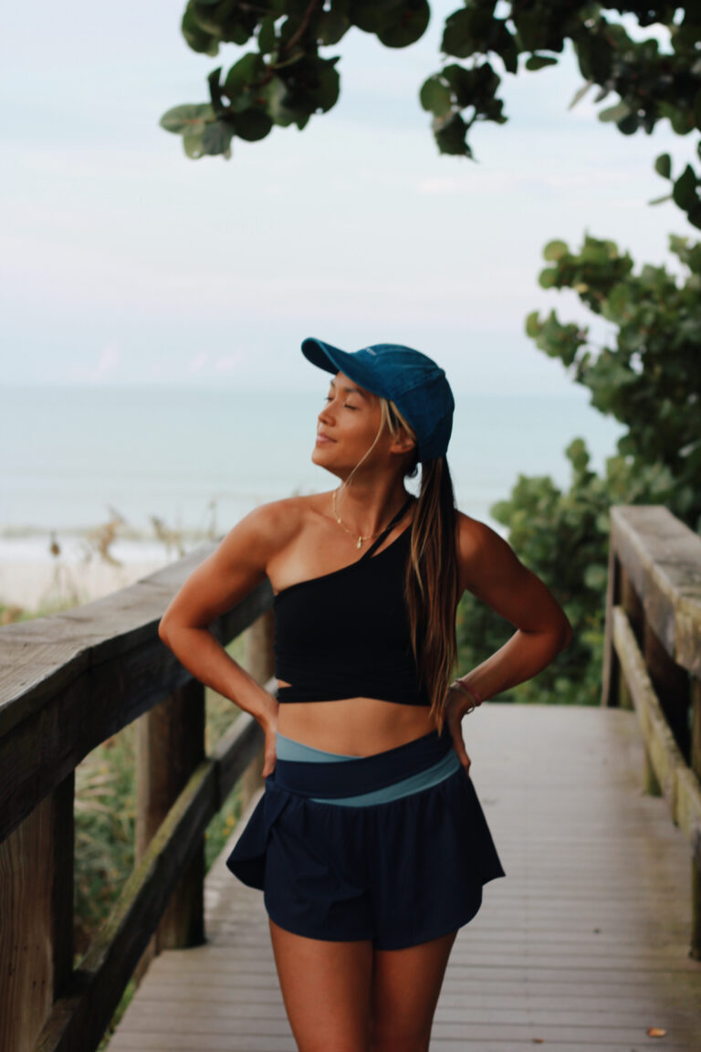 Woman in a black top and blue cap by the water